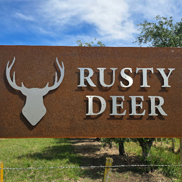Rusty Deer sign with a deer silhouette against a natural background