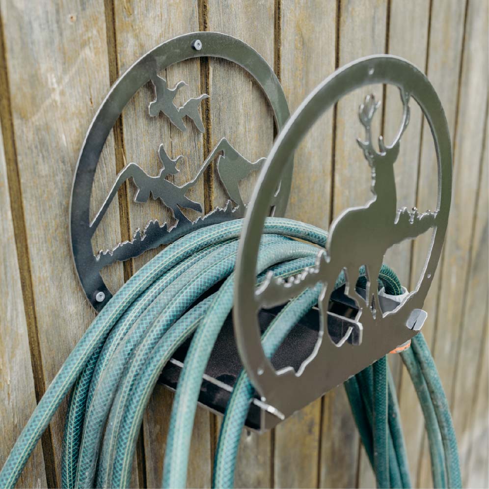 Metal hose holder with nature-themed design on a wooden background