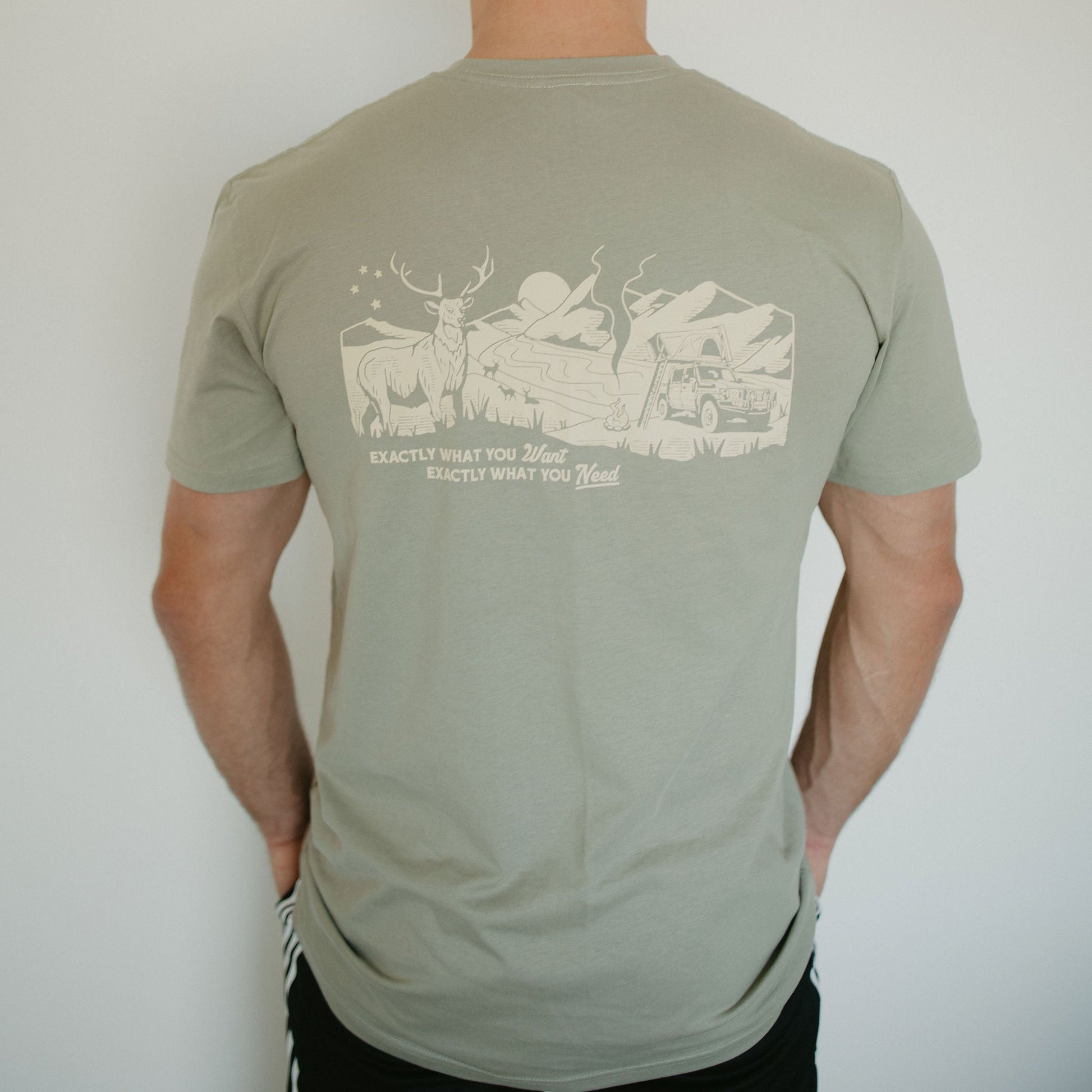 Man wearing a green t-shirt with a graphic design on the back against a white background