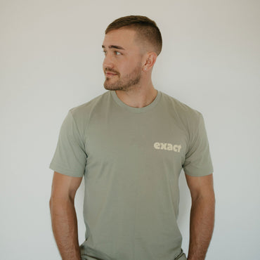 Man wearing a green t-shirt with 'exact' logo against a plain background