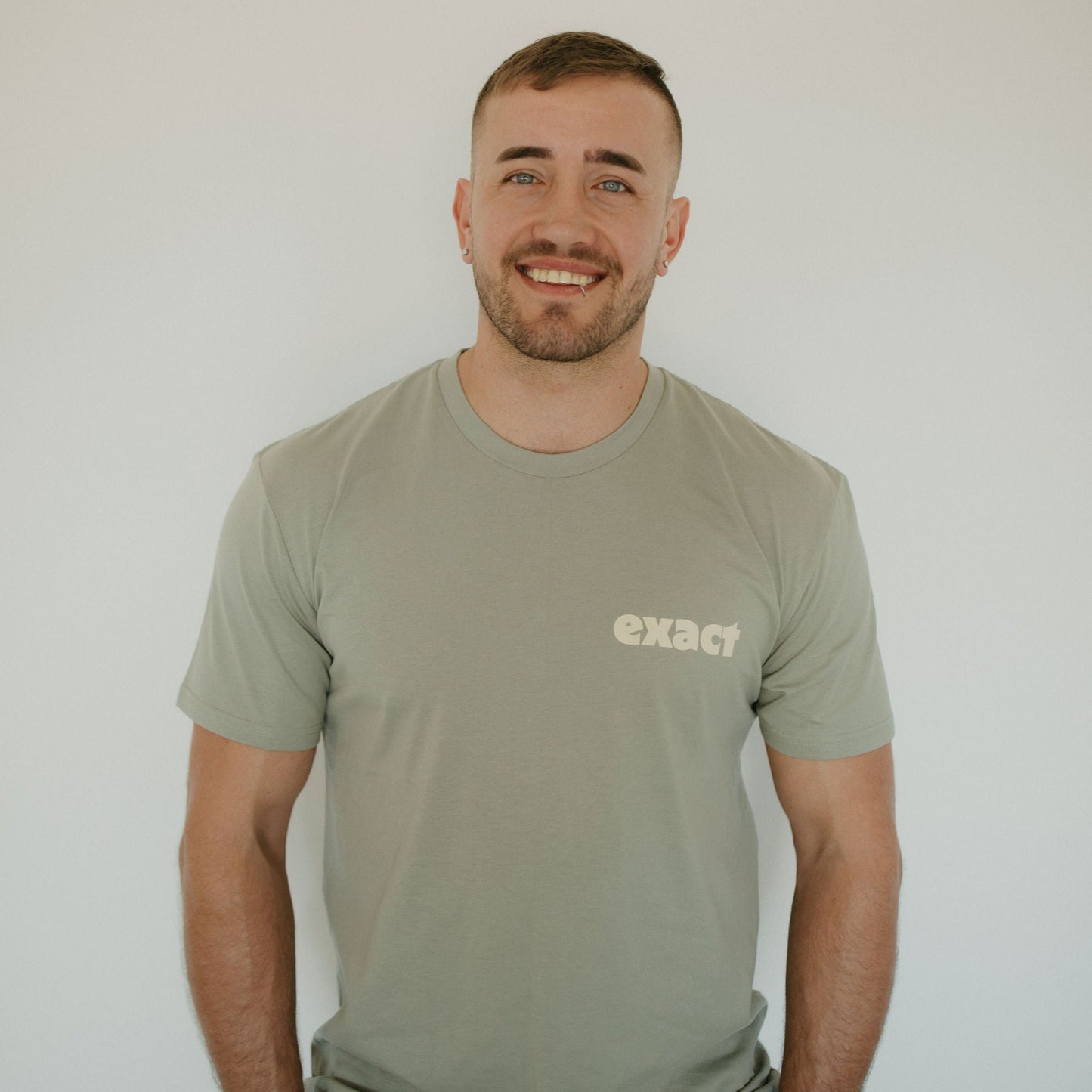 Man wearing a green t-shirt with 'exact' logo against a plain background
