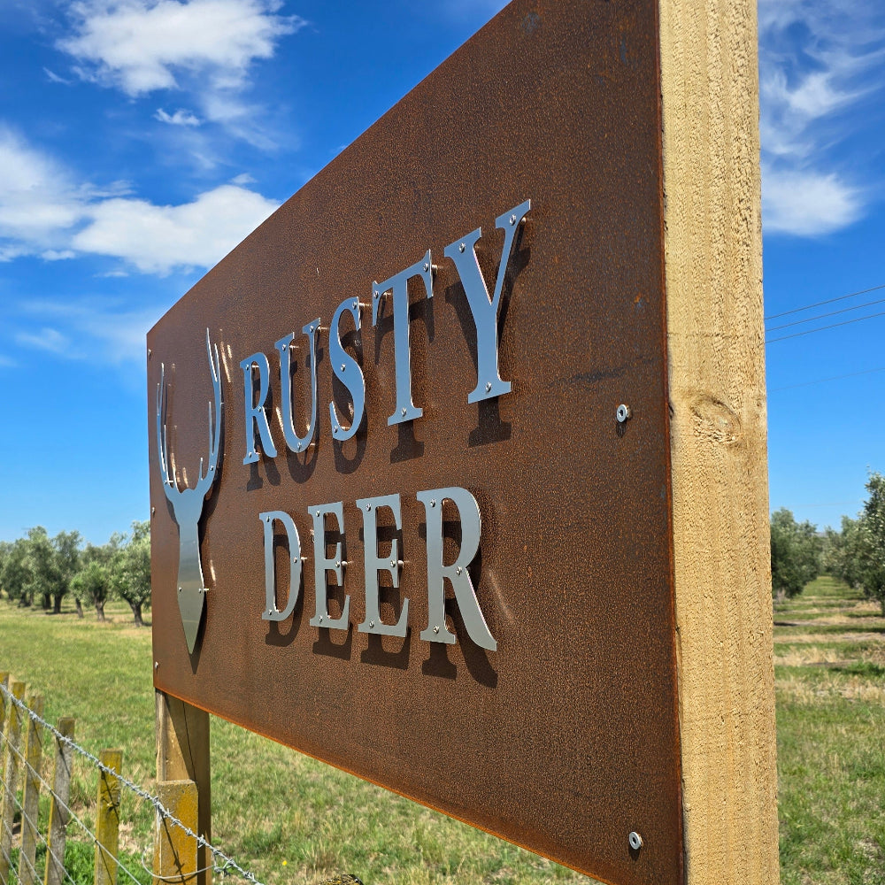 Wooden sign with 'Rusty Deer' branding against a blue sky.