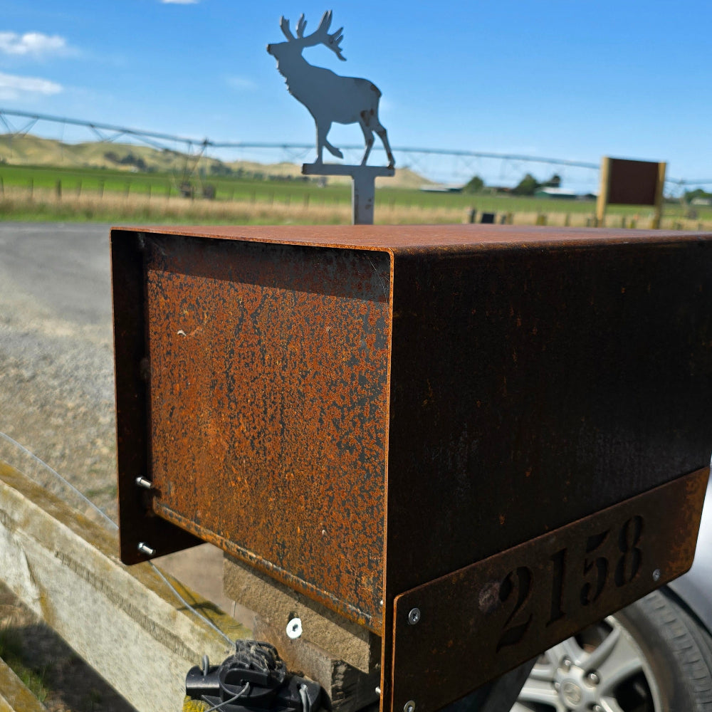 Metal sign with deer silhouette on a wooden post against a blue sky
