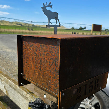 Metal sign with deer silhouette on a wooden post against a blue sky