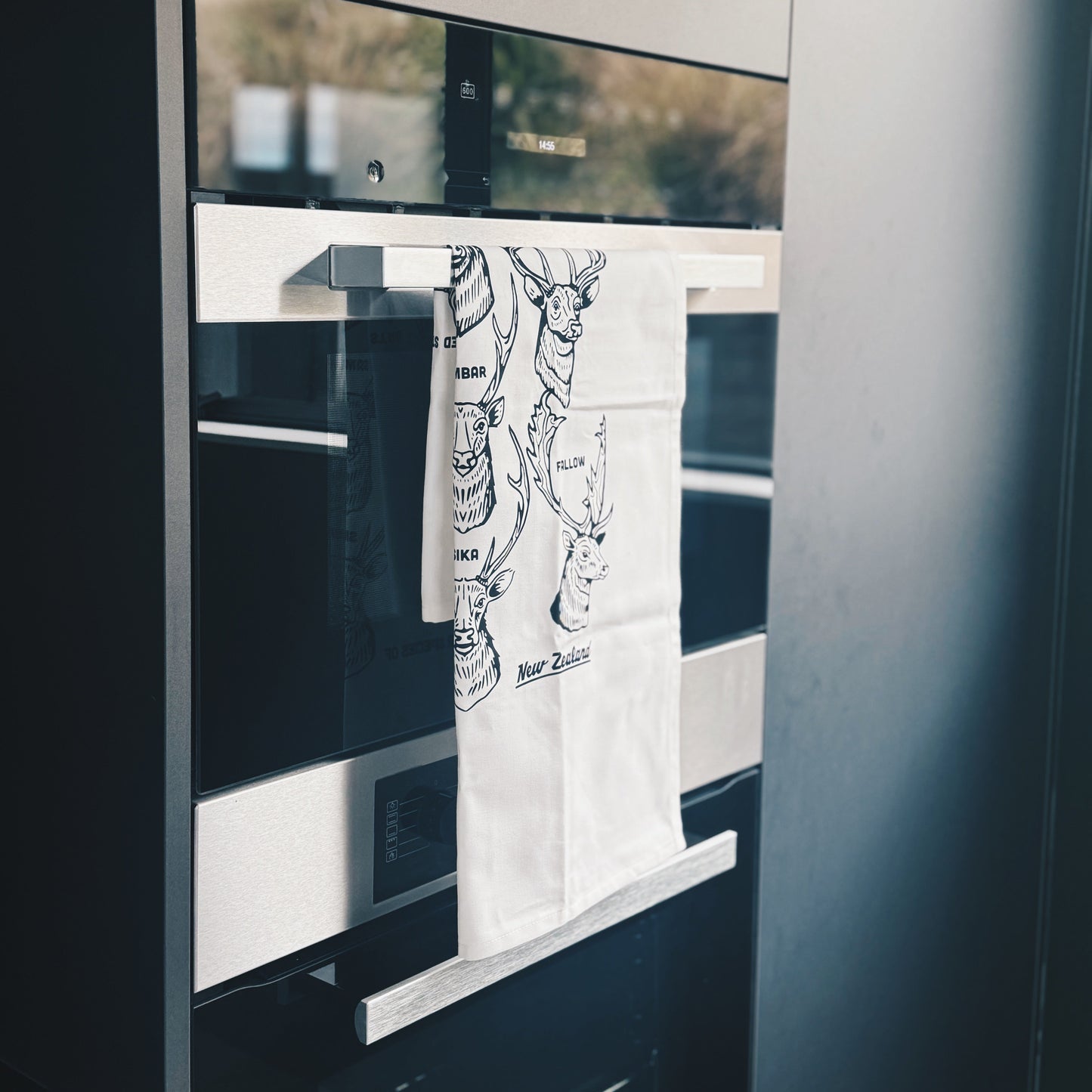 Towel with a design hanging on the handle in front of a oven.