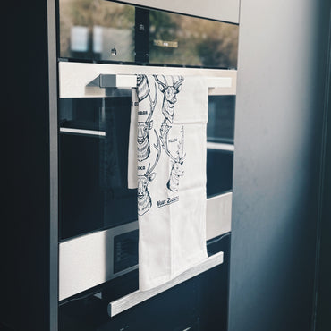 Towel with a design hanging on the handle in front of a oven.