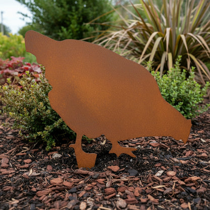Rust-colored metal Chicken silhouette on a mulched garden bed with plants in the background