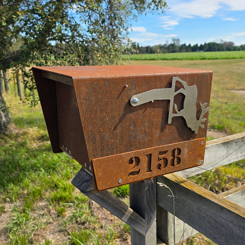 Metal sign with a bear silhouette and number '2158' attached to a wooden post outdoors.