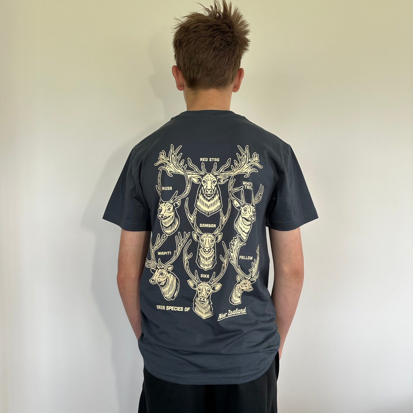 Person wearing a dark gray t-shirt with a graphic design on the back against a plain background