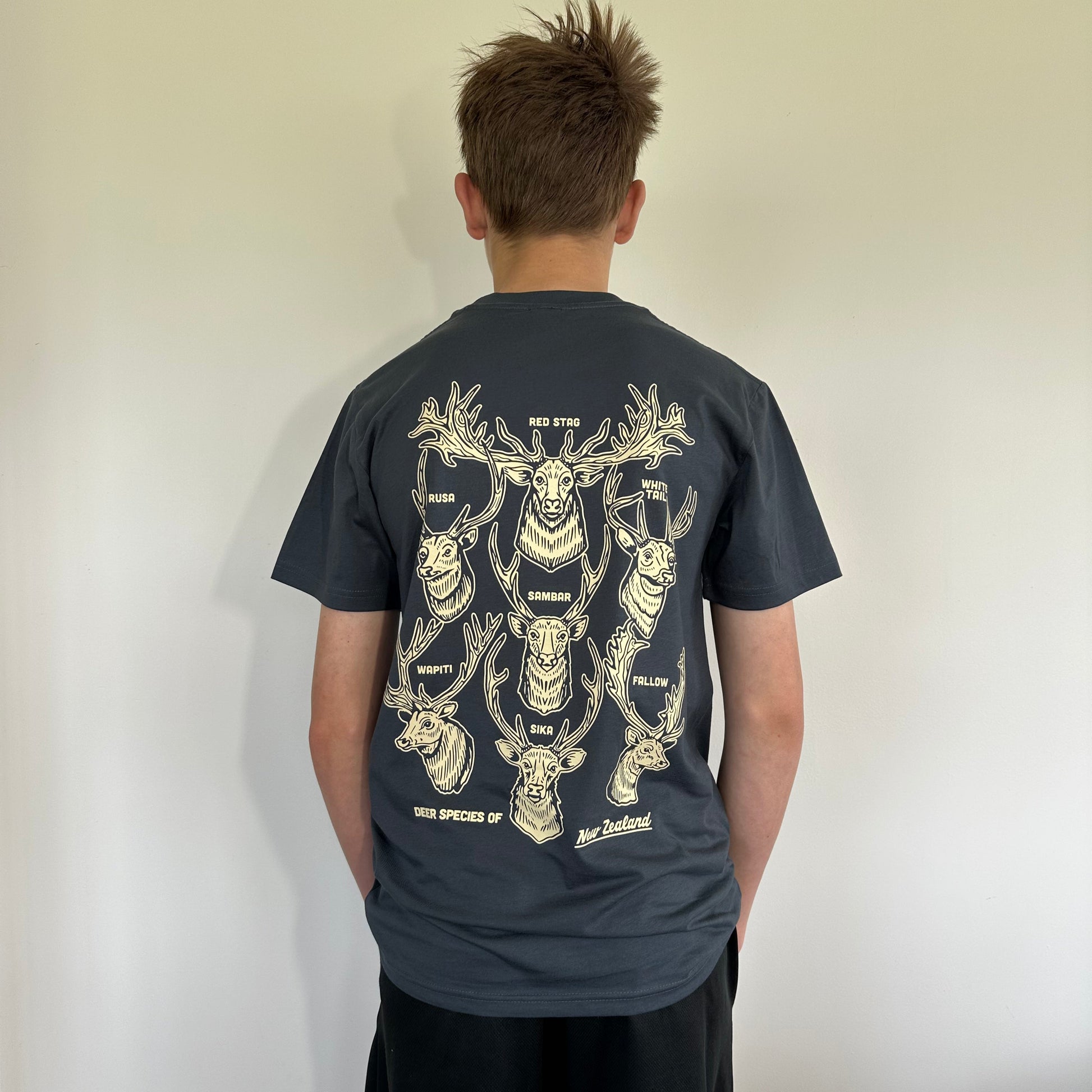 Person wearing a dark gray t-shirt with a graphic design on the back against a plain background