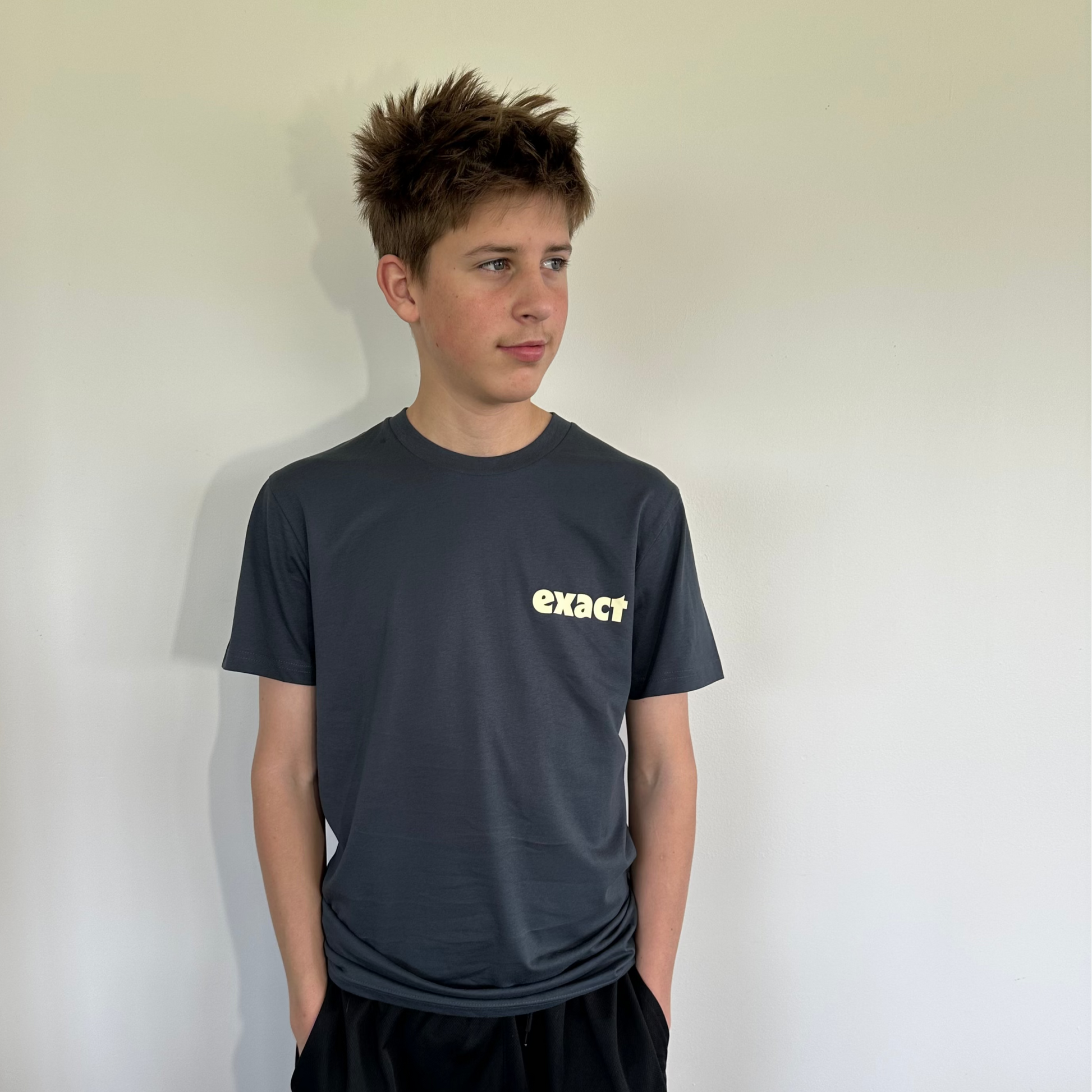 Person wearing a black 'exacq' t-shirt and black Nike shorts against a plain background