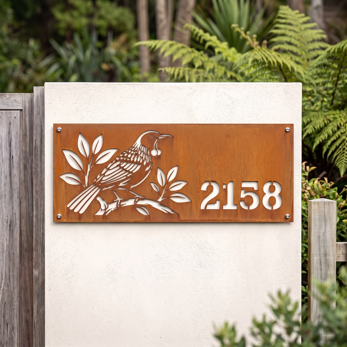 Tui House Number in weathered Corten steel without backing, installed beside a garden entrance; example number 2158.