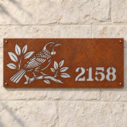 Tui House Number in weathered Corten steel with brushed stainless steel backing, front hero view on a stone wall; example number 2158.